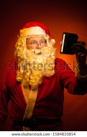 Portrait Santa Claus, old man posing on a dark red background.