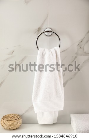 Holder with clean towel on light wall in bathroom