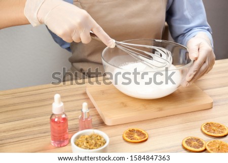 Woman making natural handmade soap at wooden table, closeup