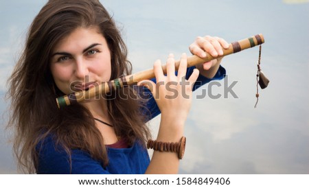 Musician playing a wooden flute on the banks of the river