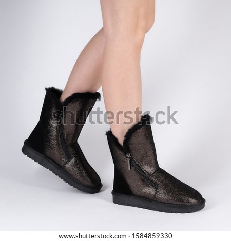 Stylish womens soft warm winter boots with fur inside. Photo on legs of a model on a white background