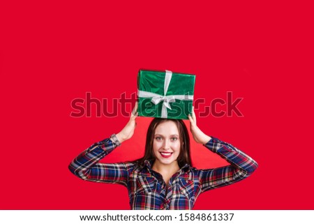 Beautiful girl holding hands gift on her head on a red background. Space for text