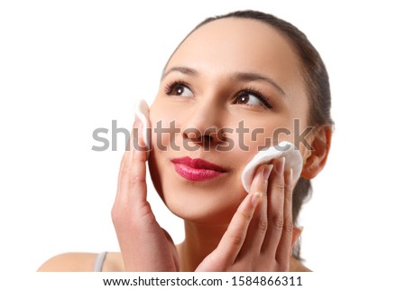 A picture of a happy woman cleaning her face with cotton pads isolated on white background