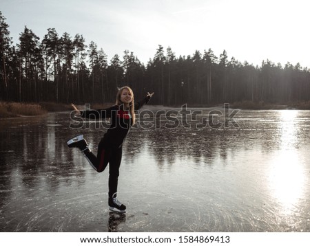 Girl skates on the ice of a forest lake raises her leg.
