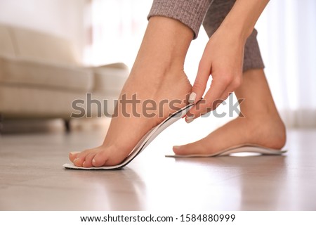 Woman fitting orthopedic insole at home, closeup Royalty-Free Stock Photo #1584880999