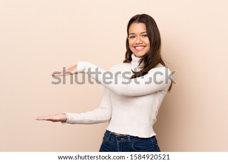 Young Colombian girl over isolated background holding copyspace to insert an ad