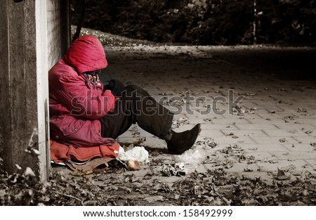 A woman sitting against a brick building with her head in her arms Royalty-Free Stock Photo #158492999