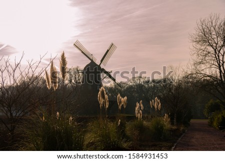 The old windmill Slottsmöllan is placed in a public park while the winter sun sets over the city