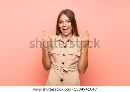 Lithuanian blonde girl over isolated pink background making rock gesture