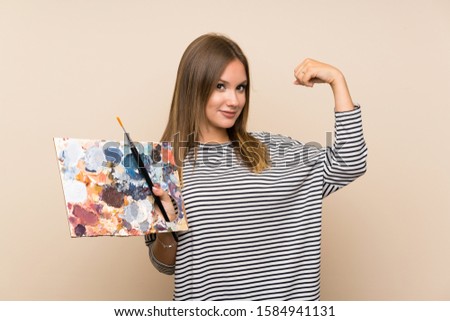 Teenager girl holding a palette over isolated background making strong gesture