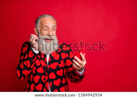Photo of funny mature guy hold telephone chatting girlfriend write love sms letter read surprise news wear stylish hearts pattern suit blazer shirt tie isolated red color background