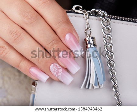 Hand with long artificial manicured nails with ombre gradient design in pink and white colors
