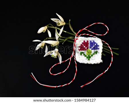 Traditional sewing pattern with red and white string, known as Martisor. It is a Romanian traditional symbol of the beginning of spring. Isolated on black background.
