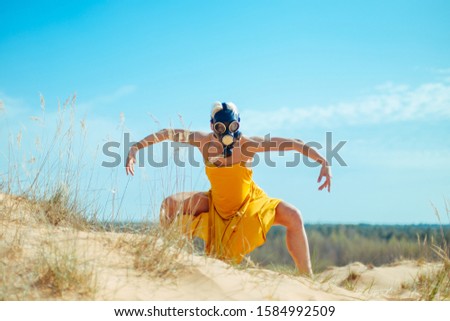 Girls in yellow dress and Gasmask dancing on the sand dunes during covid-19 coronavirus virus