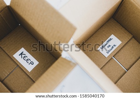 decluttering and tidying up conceptual still-life, white storage boxes to sort between objects to keep and those to declutter or donate with respective labels Royalty-Free Stock Photo #1585040170