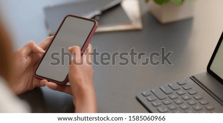 Cropped shot young businesswoman holding blank screen smartphone while working on her project 