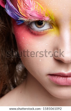 Girl looking sneakily. Close-up  shot of female face. Woman with bright stylish eyes make-up and false fashion feather eyelashes 
