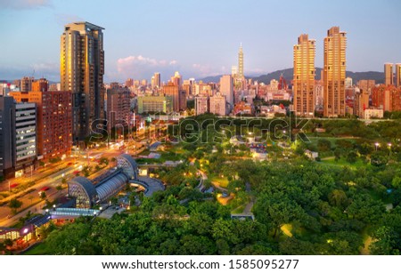 Urban skyline of Taipei City at sunset viewed from Daan Forest Park, with residential buildings surrounding the oasis & 101 Tower standing out amid high-rise office blocks in Xinyi Commercial District Royalty-Free Stock Photo #1585095277