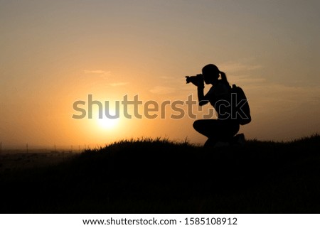 unrecognizable photographer taking photos above a mountain in backlight