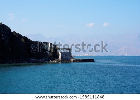 Azure sea and vintage beach building by mountains in sunny day