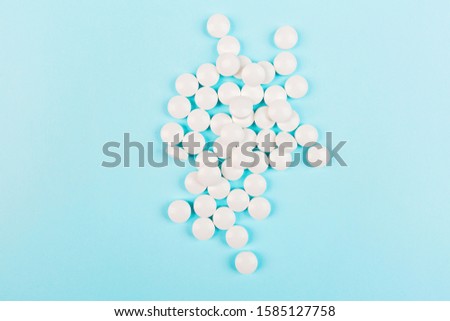 White pills on a pastel blue background. Flat lay, top view, overhead, mockup, template, copy space. Pharmacy and medical concept