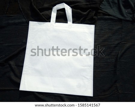 handle loop eco friendly White color shopping bags lying on black background , non woven 