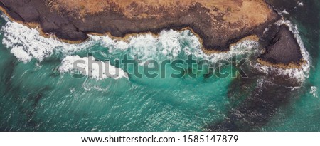 Aerial view of  sea waves breaking on rocky cliff, adventure summer travel vacation, perseverance and resilience, hydropower clean renewable energy, decarbonisation concept Royalty-Free Stock Photo #1585147879