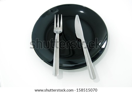 Shiny new cutlery, silverware on black  plate close-up on white background