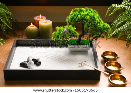 Beautiful miniature zen garden, candles and oil lamps on table