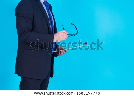 businessman with glasses in one hand and reports in the other