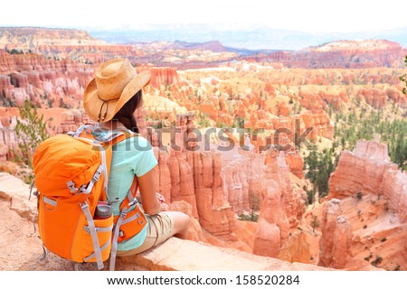 Hiker woman in Bryce Canyon hiking looking and enjoying view during her hike wearing hikers backpack. Bryce Canyon National Park landscape, Utah, United States.