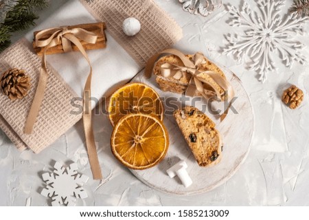 Cinnamon sticks are tied with a ribbon on a beige napkin with slices of dried orange, pine cone, nuts, snowflakes and marshmallows near a fir branch. Christmas concept. Flat lay