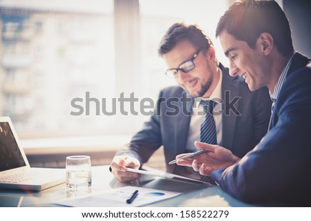 Image of two young businessmen using touchpad at meeting Royalty-Free Stock Photo #158522279