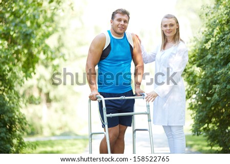 Pretty nurse and male patient looking at camera in park Royalty-Free Stock Photo #158522765