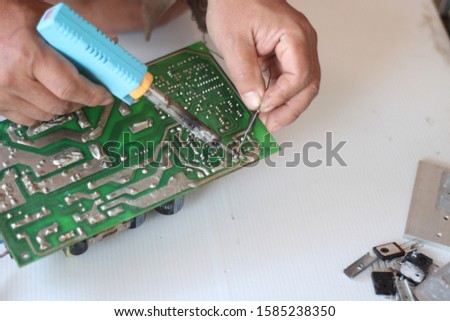 Closeup of a technician's hands soldering a computer mainboard