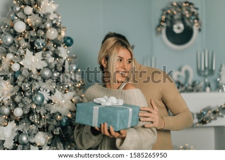 picture of romantic couple in a sweaters with gift box. Boy give a Christmas gift to her girlfriend. Happy young couple background. Magic card.