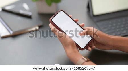 Close-up view of young professional businesswoman holding blank screen smartphone in her office room 