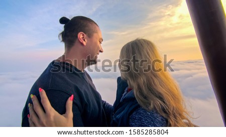 Adventure love couple on hot air balloon watermelon. Man and woman kiss hug love each other. Burner directing flame into envelope. Fly in morning blue sky. Happy people take selfie in hot air ballon.