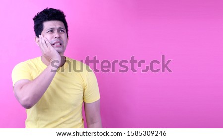 Young  Asia man with a  toothacheon pink background in studio With copy space.
