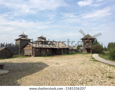 View of the old abandoned settlement of log houses and mills against the blue sky. Mobile photo in natural daylight in Russia.