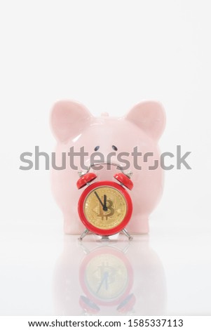Concept image illustrating a deadline to invest in cryptocurrency showing a pink piggy bank and a red alarm clock with a bitcoin as the clock face.