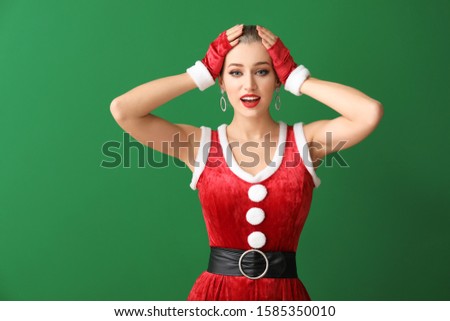 Beautiful young woman dressed as Santa on color background