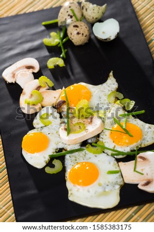 Plate with scrambled quail eggs with champignons mushrooms  on table