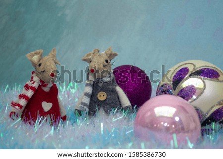 Two decorative toy mice are on the tinsel and lie next to a Christmas balls