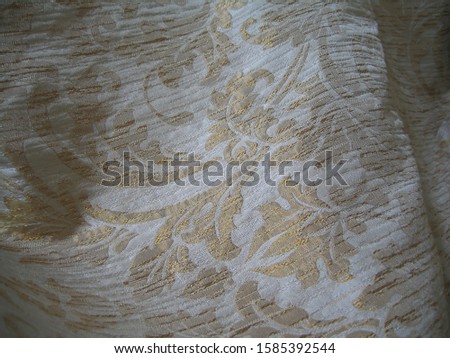 beautiful fabric drapery with macro shot.a piece of silk white fabric with almost a gold ornament