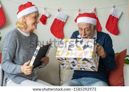 Senior couple open big gift presents box and happy together at home for Christmas festival day, Retirement lifestyle concept