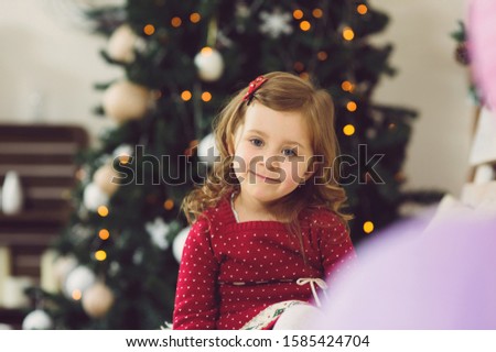 smiling girl sitting at Christams tree