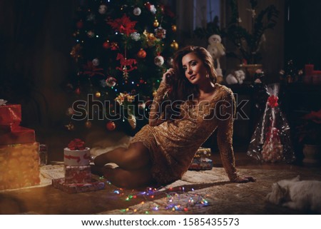 Attractive young woman sits near Christmas tree