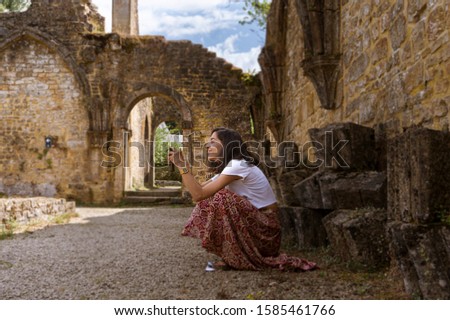 Girl tourist takes a picture at the Abbey of Orval, in Belgium. Ruins of the Cistercian monastery and the Gothic church. Travel by car in summer