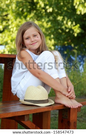 Pretty smiling little girl with long healthy hair outdoors in the summer